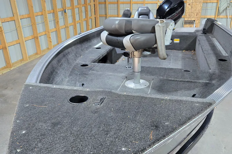 Slide: The Image of 2014 Lund 1650 Rebel Tiller boat interior with seating and motor in a garage. - 4