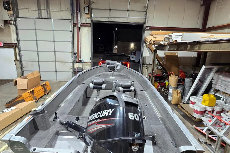 Slide: The Image of 2014 Lund 1650 Rebel Tiller boat with Mercury 60 engine in a garage setting. - 5