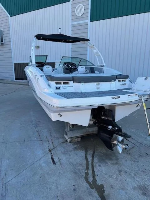Slide: The Image of 2020 Chaparral 23 SSi boat with black canopy, docked outside a building. - 3