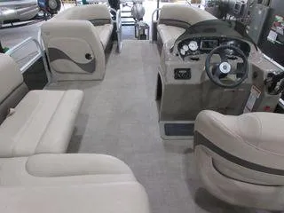 Slide: The Image of 2023 Sun Tracker Party Barge 18 DLX interior with beige seating and steering console. - 5