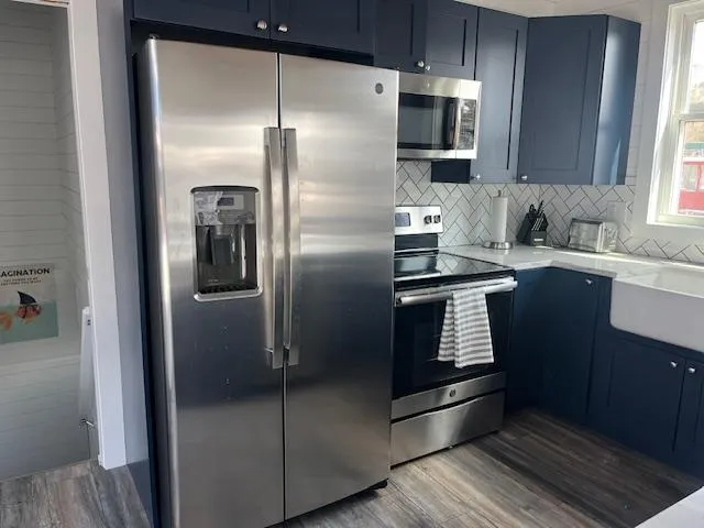Slide: The Image of Modern kitchen with stainless steel appliances, blue cabinets, and herringbone backsplash in a 2020 Harbor Cottage. - 12
