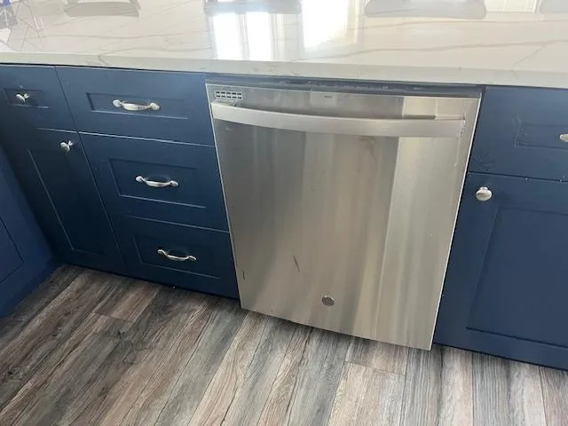 Slide: The Image of Modern kitchen with stainless steel dishwasher, blue cabinets, and wood flooring in a Harbor Cottage 16 x 84. - 17
