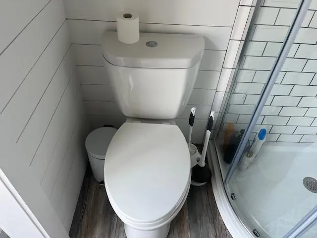 Slide: The Image of Modern bathroom with toilet, shower, and white subway tiles in a Harbor Cottage 16 x 84 model. - 23