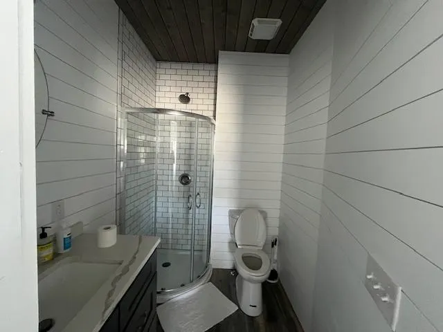 Slide: The Image of Modern bathroom with glass shower, white shiplap walls, and dark wood accents in Harbor Cottage model. - 29