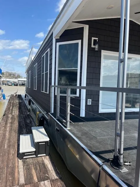 Slide: The Image of Modern 2020 Harbor Cottage houseboat, model 16 x 84, docked under a clear blue sky. - 3