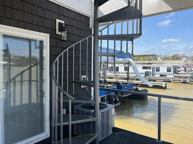Slide: The Image of Spiral staircase on a 2020 Harbor Cottage houseboat, overlooking a marina with calm waters. - 36