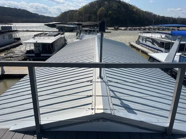 Slide: The Image of Houseboat with metal roof docked at marina, surrounded by water and hills. - 38
