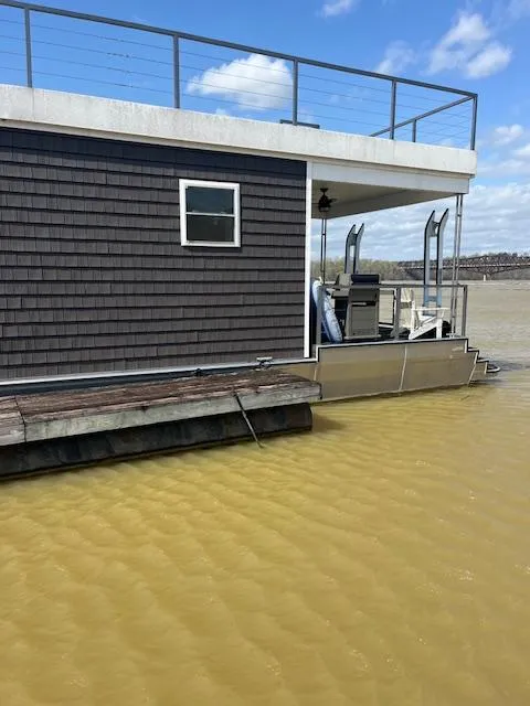 Slide: The Image of Modern 2020 Harbor Cottage houseboat on water, featuring sleek design and rooftop railing. - 4