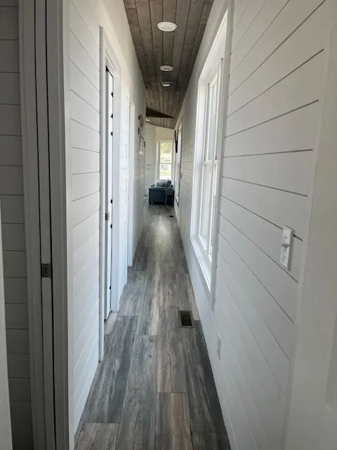 Slide: The Image of Narrow hallway in 2020 Harbor Cottage model, featuring white shiplap walls and wood flooring. - 40