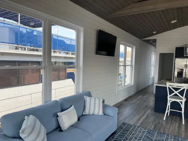 Slide: The Image of Modern houseboat interior with blue sofa, wall-mounted TV, and large windows. Harbor Cottage 16 x 84, 2020. - 6