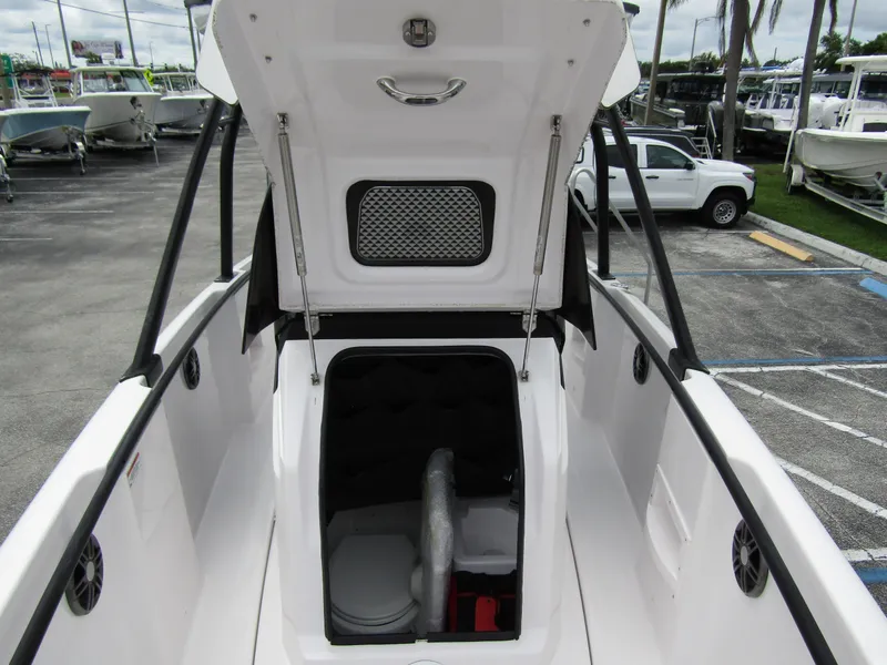 Slide: The Image of 2022 Axopar 22 T-Top boat with open storage compartment, docked in a marina. - 10