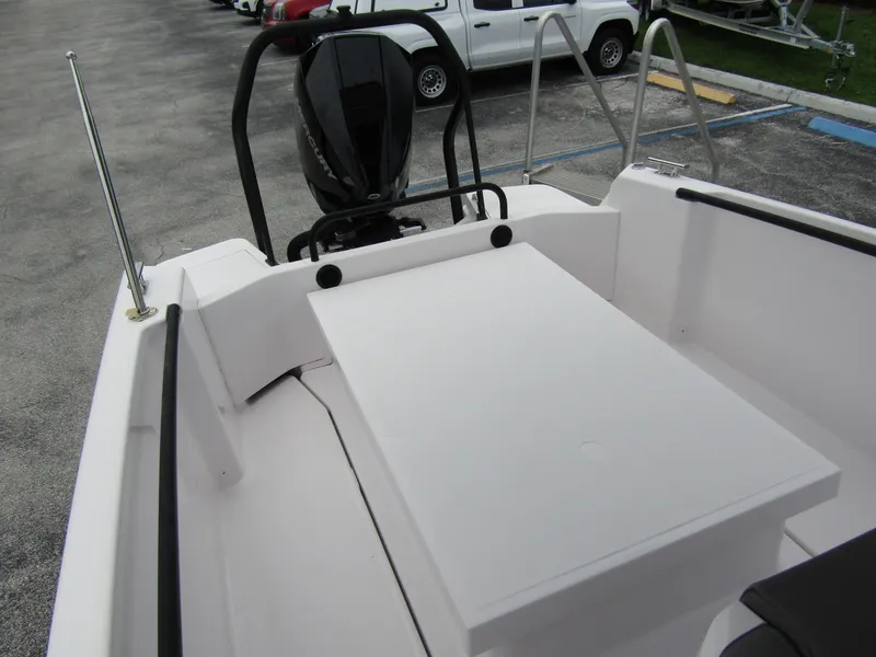 Slide: The Image of 2022 Axopar 22 T-Top boat interior with seating and motor, parked on concrete. - 18