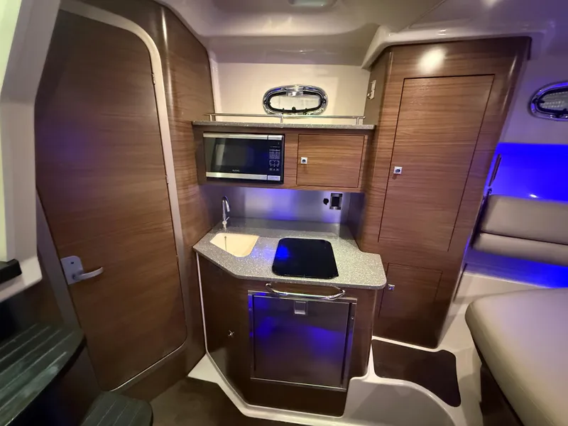 Slide: The Image of 2018 Boston Whaler 345 Conquest interior with kitchenette, featuring wood cabinetry and modern appliances. - 21