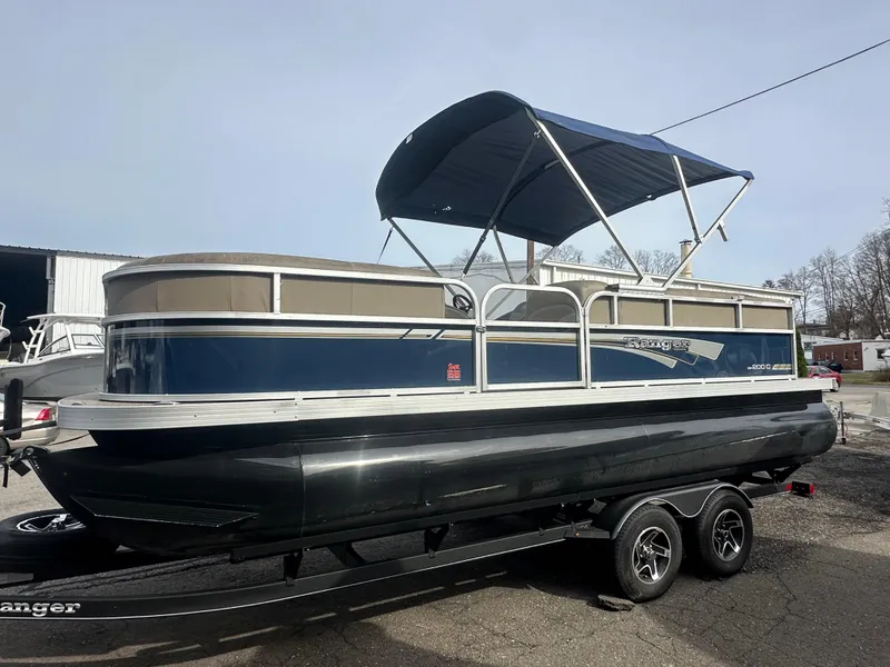 Slide: The Image of 2023 Ranger Reata 200C pontoon boat with blue canopy on trailer. - 0
