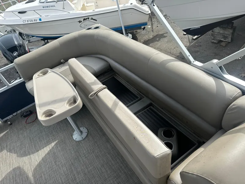 Slide: The Image of 2023 Ranger Reata 200C boat interior with beige seating and table, featuring cup holders. - 10