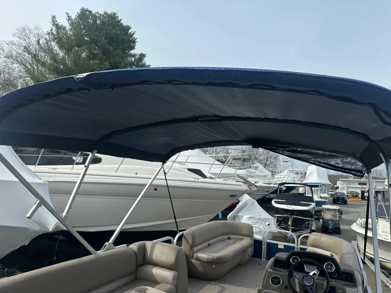 Slide: The Image of 2023 Ranger Reata 200C pontoon boat with canopy, docked among other boats. - 11