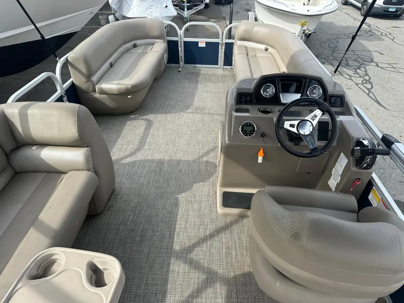 Slide: The Image of 2023 Ranger Reata 200C pontoon boat interior with beige seating and steering console. - 12
