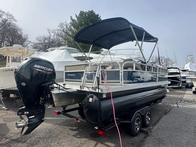 Slide: The Image of 2023 Ranger Reata 200C pontoon boat with Mercury outboard motor, parked on a trailer. - 6