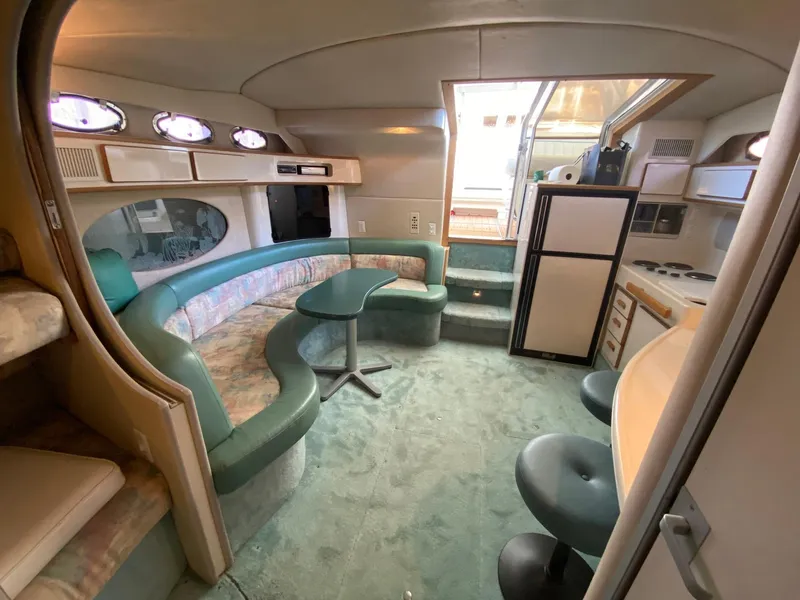 Slide: The Image of Interior of 1995 Sea Ray 400 Express Cruiser with seating, table, and kitchenette. - 17