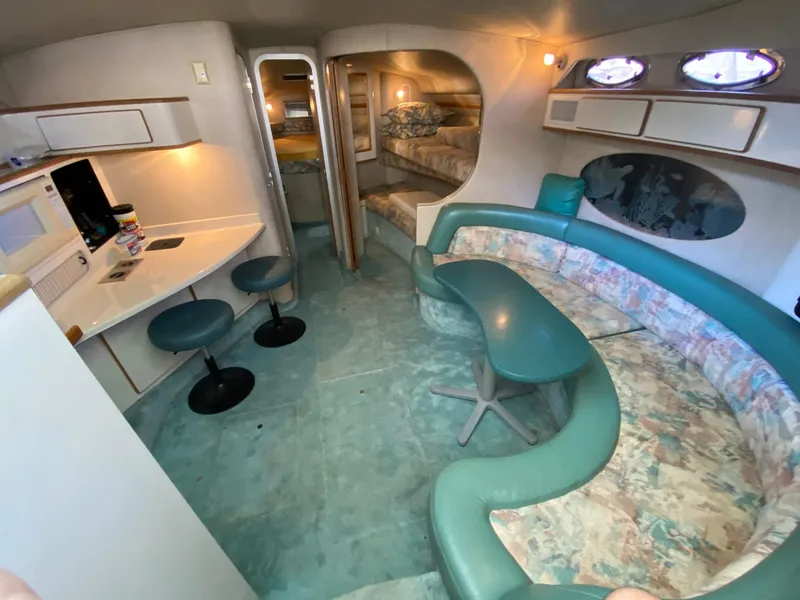 Slide: The Image of 1995 Sea Ray 400 Express Cruiser interior with teal seating, dining area, and compact kitchen. - 18