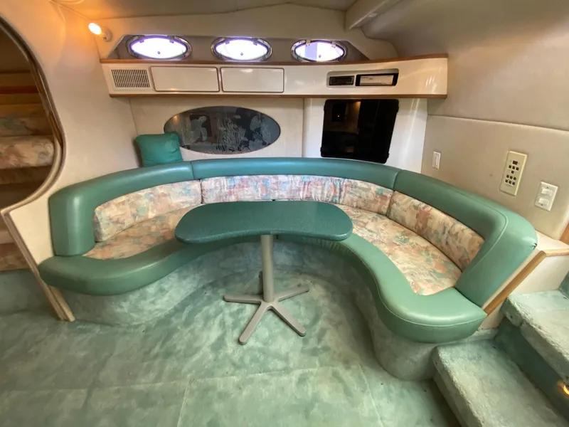 Slide: The Image of 1995 Sea Ray 400 Express Cruiser interior with green seating and table, featuring porthole windows. - 19