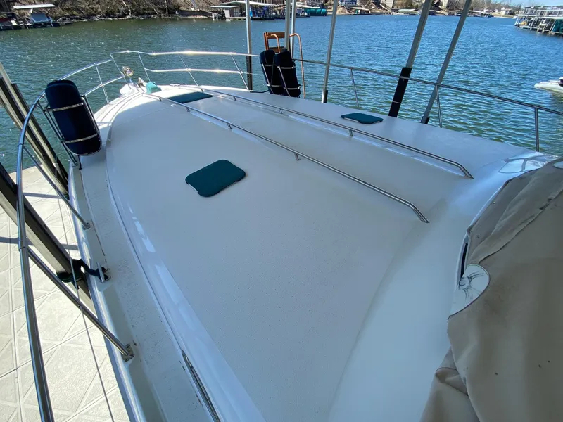 Slide: The Image of 1995 Sea Ray 400 Express Cruiser deck with railings, docked by a serene lake. - 5