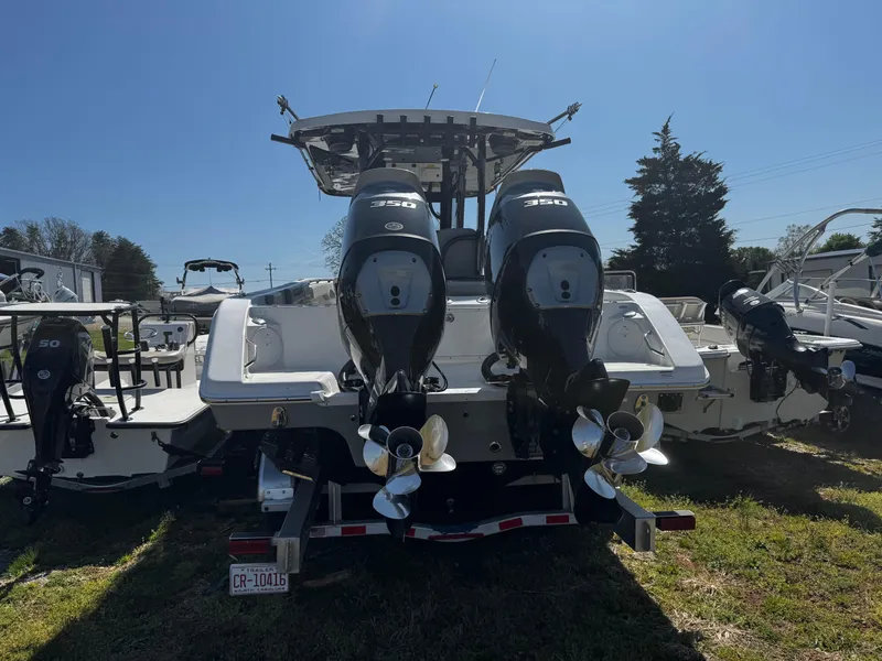 Slide: The Image of 2023 Sea Pro 320 DLX Center Console boat with dual outboard motors, parked on grass. - 2