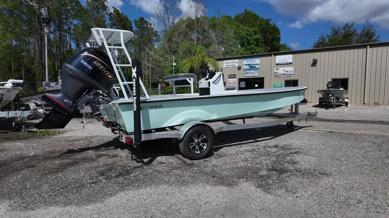 Slide: The Image of 2025 Xpress Skiff 185 boat on trailer, parked outdoors near a building. - 12