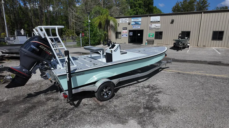 Slide: The Image of 2025 Xpress Skiff 185 boat on trailer outside a building, sunny day. - 13