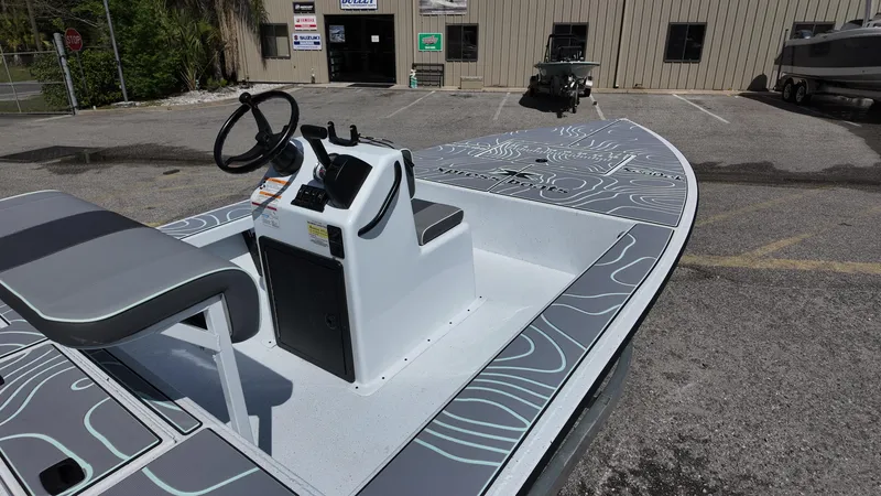 Slide: The Image of 2025 Xpress Skiff 185 boat with modern design, parked outdoors near a building. - 18