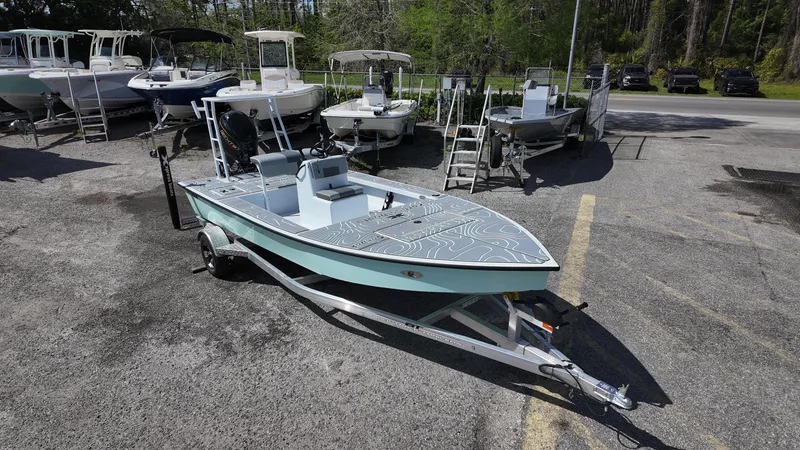 Slide: The Image of 2025 Xpress Skiff 185 boat on trailer in outdoor showroom. - 2