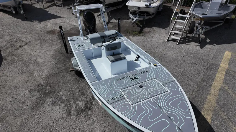 Slide: The Image of 2025 Xpress Skiff 185 boat with custom deck design, parked on gravel lot. - 22