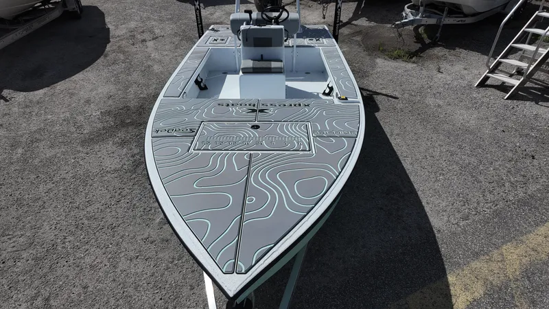 Slide: The Image of 2025 Xpress Skiff 185 boat with topographic deck design, parked on concrete. - 25