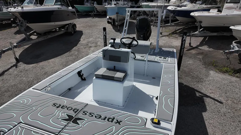 Slide: The Image of 2025 Xpress Skiff 185 boat with center console, parked among other boats. - 26