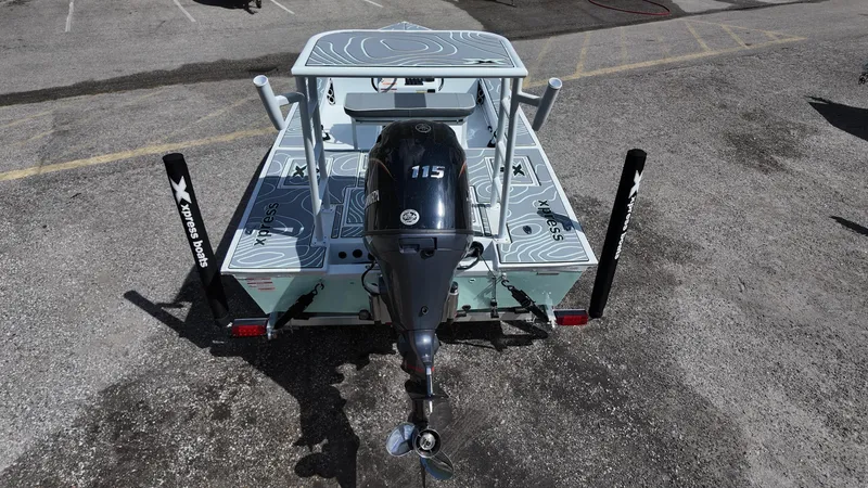 Slide: The Image of 2025 Xpress Skiff 185 boat with outboard motor, viewed from the rear on a concrete surface. - 33