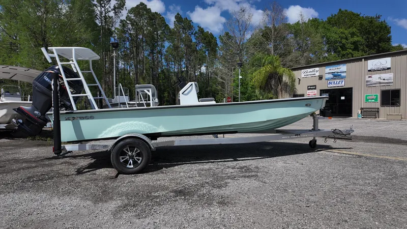 Slide: The Image of 2025 Xpress Skiff 185 boat on trailer, parked outdoors near a building. - 9