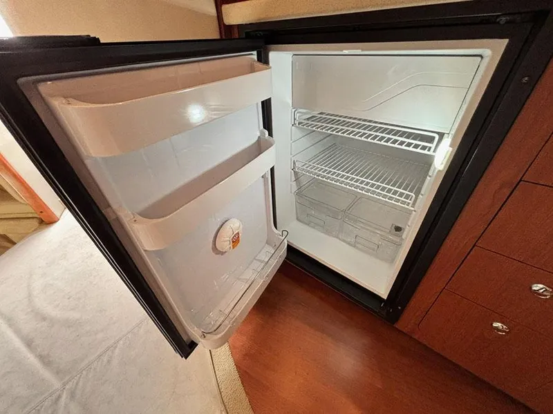 Slide: The Image of Open refrigerator inside 2004 Chaparral 350 Signature boat, showing empty shelves and door storage. - 19