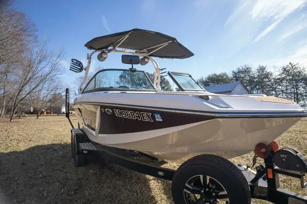 Slide: The Image of 2017 Correct Craft Super Air Nautique GS boat on trailer, parked on grass under clear sky. - 2