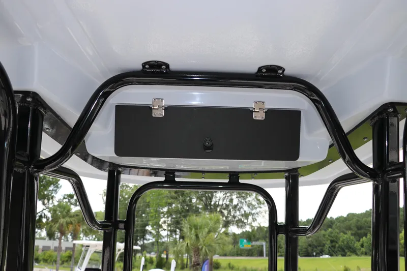 Slide: The Image of 2025 Robalo 226 Cayman boat T-top storage compartment with black frame and latch. - 19
