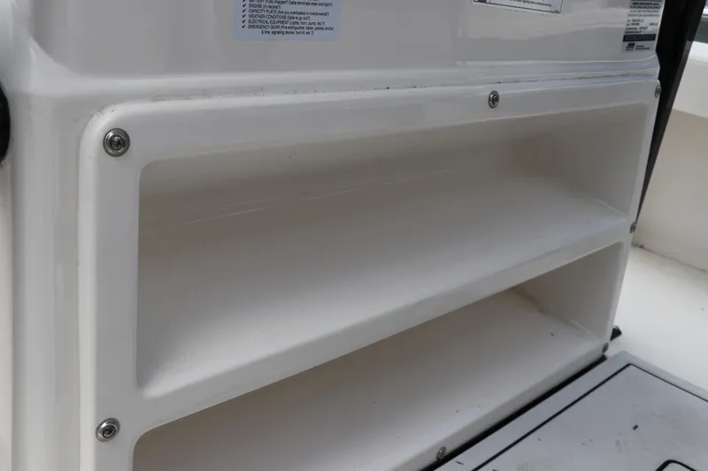 Slide: The Image of Storage compartment on 2025 Robalo 226 Cayman boat, featuring white shelves and secure fastenings. - 24