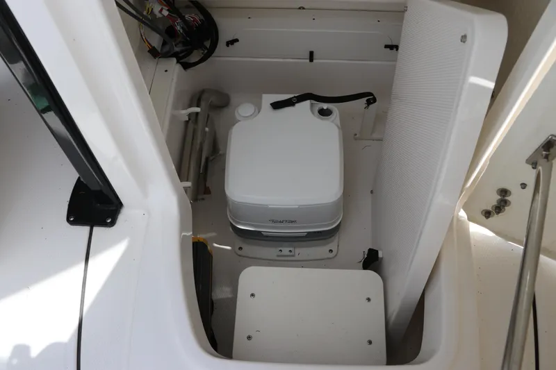 Slide: The Image of 2025 Robalo 226 Cayman boat interior with portable toilet and storage compartment. - 28