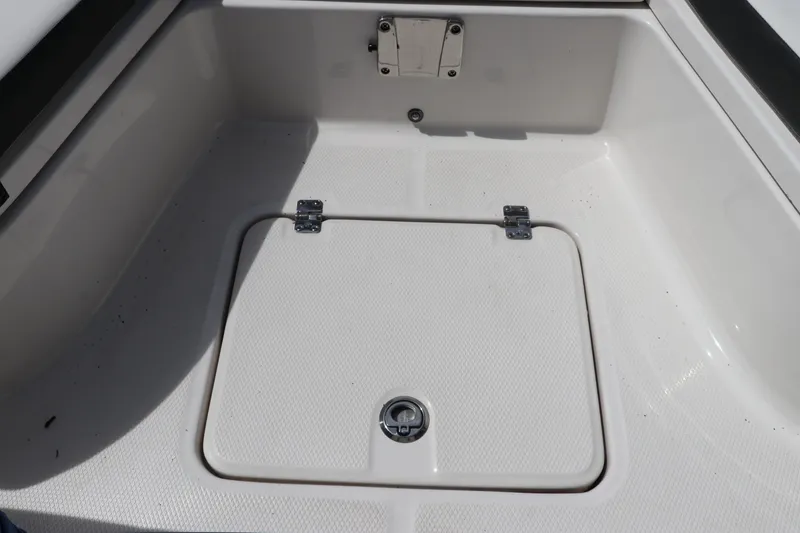 Slide: The Image of 2025 Robalo 226 Cayman boat storage compartment with secure latch and clean white finish. - 39