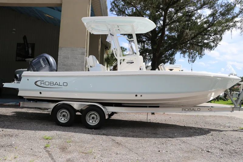 Slide: The Image of 2025 Robalo 226 Cayman boat on trailer, parked outdoors. - 1