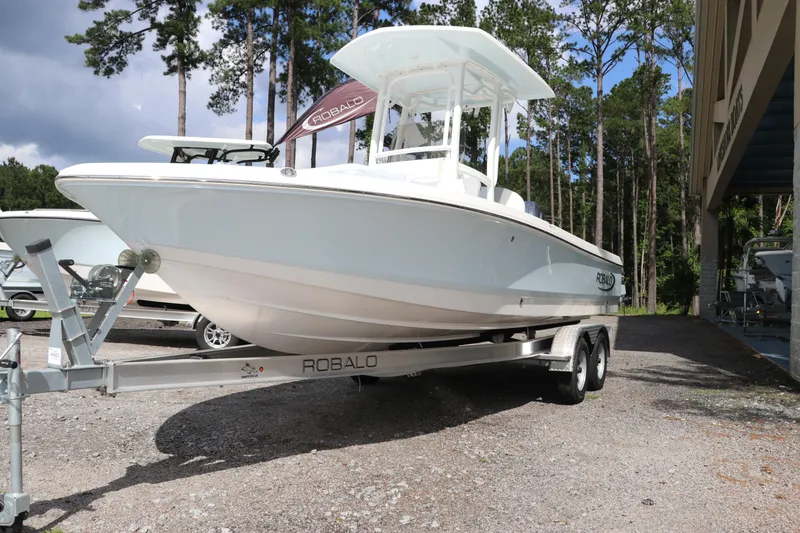 Slide: The Image of 2025 Robalo 226 Cayman boat on trailer, parked outdoors near trees. - 3