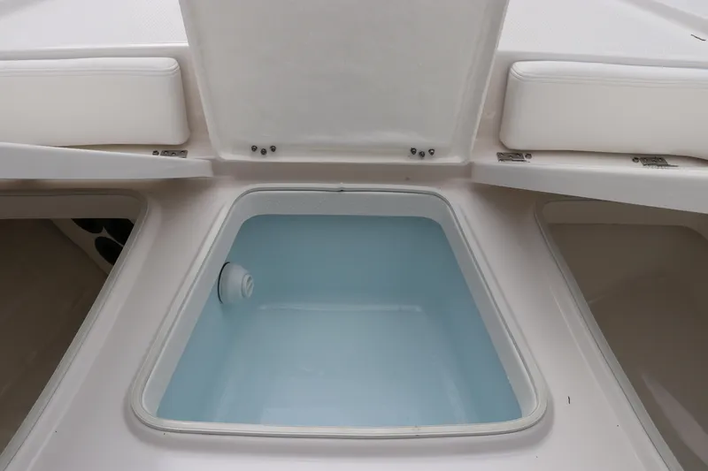 Slide: The Image of 2025 Robalo 226 Cayman boat storage compartment with open hatch and cushioned seating. - 35