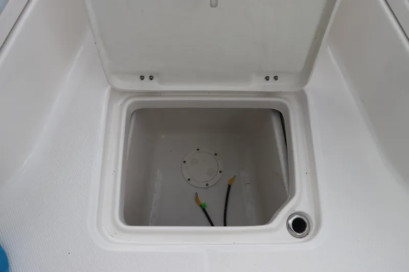 Slide: The Image of 2025 Robalo 226 Cayman boat storage compartment, open lid, white interior. - 40