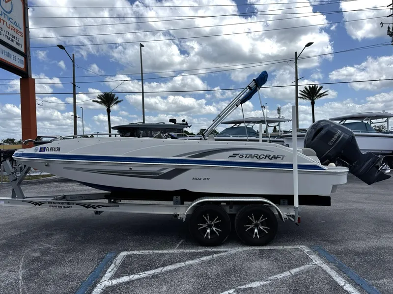 Slide: The Image of 2020 Starcraft MDX 211 OB boat on trailer, parked outdoors under cloudy sky. - 0
