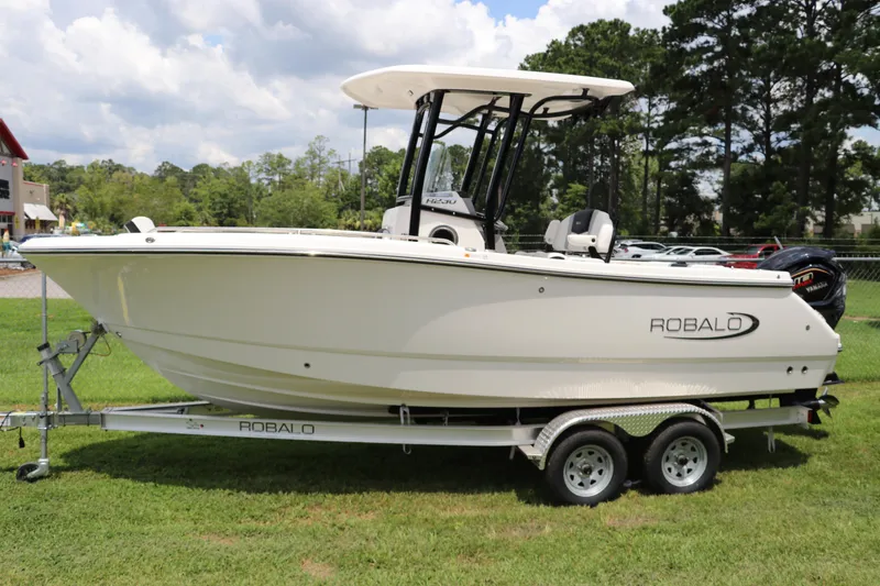 Slide: The Image of 2024 Robalo R230 Center Console boat on trailer, parked on grass. - 0