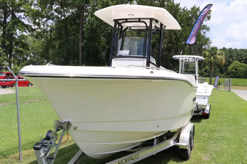Slide: The Image of 2024 Robalo R230 Center Console boat on trailer, parked on grass. - 1