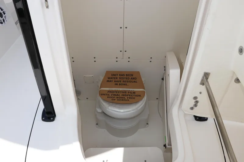 Slide: The Image of 2024 Robalo R230 Center Console boat interior with toilet and protective film. - 24